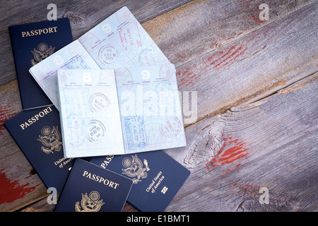 American passports lying on a rustic wooden table open to reveal hand stamps from customs officials on border control applied du Stock Photo