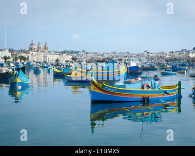 A fisherman in a luzzu, a traditional Maltese fishing boat, in colourful Marsaxlokk, Malta. Stock Photo