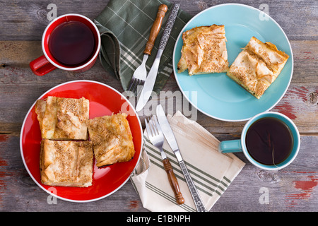 Tea for two at a spring picnic with cups of steaming hot tea and side plates with slices of freshly baked homemade borek pastry Stock Photo