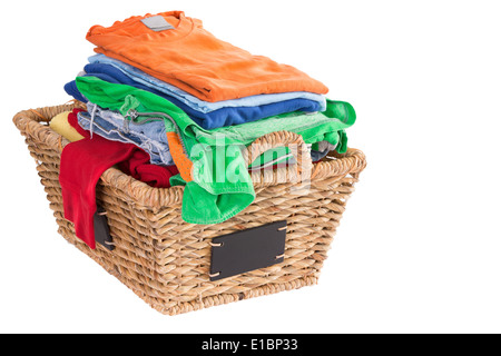 Colorful collection of clean washed fresh summer clothes in a rustic woven wicker laundry basket with blank attached labels Stock Photo