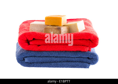 Two colorful neatly soft fluffy folded cotton towels with bars of organic herbal soap isolated on white for a healthy aromatic b Stock Photo