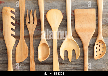 Set of rustic wooden handcrafted kitchen utensils with a spaghetti strainer, spoons , spatula and salad servers arranged in an a Stock Photo