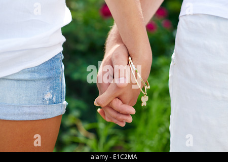 Close-up of female and male holding by hands in park Stock Photo
