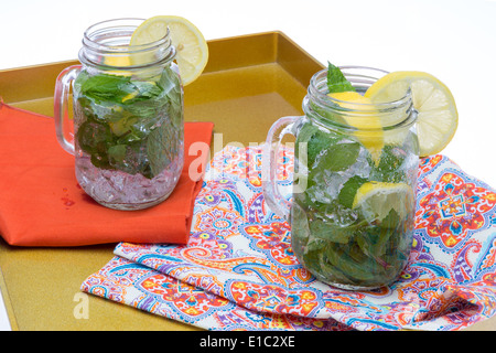 Refreshing chilled drinks lemon and mint in iced water served in glass jars garnished with lemon Stock Photo