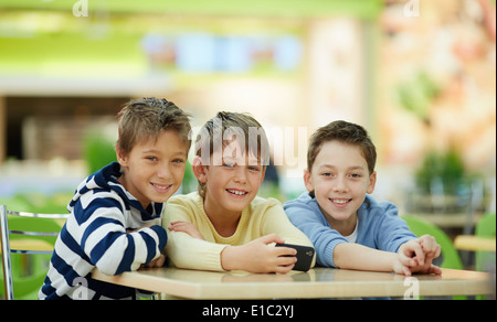 Portrait of three schoolboys sitting at table and looking at camera Stock Photo