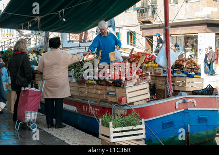 Fruit and vegetable seller selling produce to customers from canal boat in Venice, Italy Stock Photo