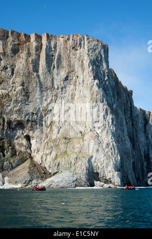 Zodiac boats with people, traveling along the cliffs in Nunavut, Canada Stock Photo