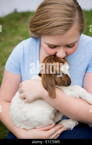 A girl cuddling a baby goat. Stock Photo
