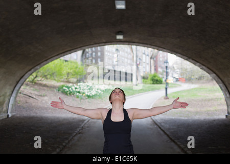 A young woman in Central Park, in a black leotard and leggings, doing yoga. Stock Photo