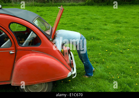 A  person leaning in to the boot at the rear of the car. Stock Photo