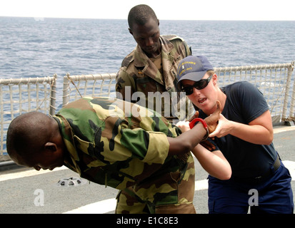 U.S. Coast Guard Ensign Kate Murray, right, demonstrates handcuffing techniques on Senegalese Seaman Jean-Rodrigue Mandy as Sen Stock Photo