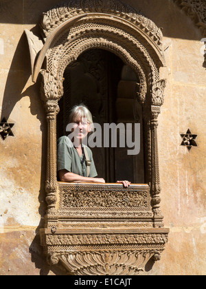 India, Rajasthan, Jaisalmer, Patwon Ki Haveli, woman tourist in decoratively carved sandstone window Stock Photo