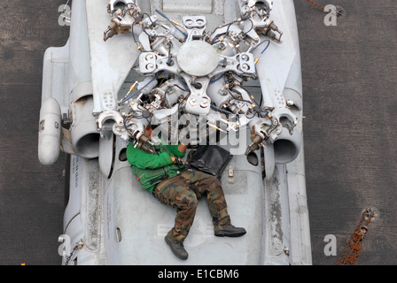 U.S. Navy Aviation Machinist's Mate Airman Felix Carcamo replaces the droop stop heating element on an SH-60F Seahawk helicopte Stock Photo