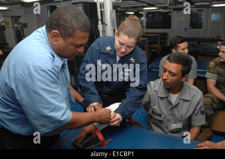 A U.S. Navy hospital corpsman 1st class demonstrates the application of a splint for a broken arm to Brazilian sailors aboard U Stock Photo