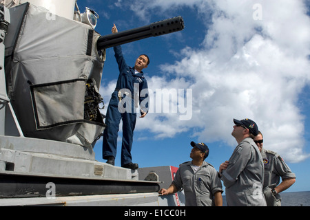 U.S. Navy Fire Controlman 2nd Class Chaung Pha explains the functions of a close-in weapons system aboard the guided-missile de Stock Photo