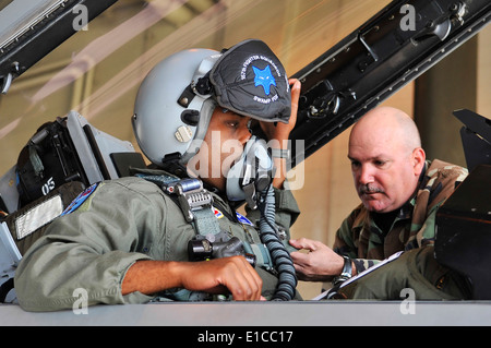 U.S. Air Force Tech. Sgt. Michael Bilberry straps Capt. Taj Troy into an F-16 Fighting Falcon aircraft in preparation for a fli Stock Photo