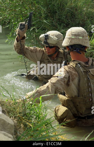 U.S. Marine Corps Lance Cpl. Helmut Eggl holds his M-9 Beretta handgun above water as he crosses a canal July 26, 2009, during Stock Photo