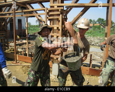 U.S. Navy Seabees from Naval Mobile Construction Battalion 40 and Indonesian marine corps engineers transfer concrete at the si Stock Photo