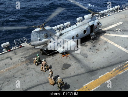 U.S. Marines board a CH-46 Sea Knight helicopter assigned to Marine Medium Helicopter Squadron 165 on the flight deck of the am Stock Photo