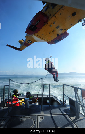 A rescue swimmer descends from a Canadian air force helicopter to a U.S. Coast Guard 41-foot boat Aug. 25, 2009, during a searc Stock Photo