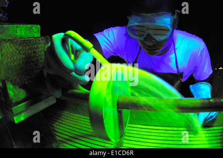 U.S. Air Force Airman 1st Class Marvin Moss uses a black light to look for surface defects on an aircraft part at Eielson Air F Stock Photo