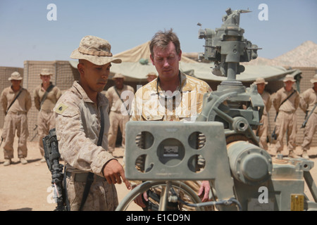 U.S. Marine Corps Sgt. Antonio Ayala, left, explains the capabilities of an M777A2 lightweight 155 mm howitzer to British Brig. Stock Photo