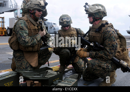 U.S. Marines load ammunition prior to conducting live-fire small arms training on the flight deck of the multipurpose amphibiou Stock Photo