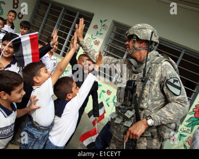 U.S. Army Sgt. Maj. Cannaballo, assigned to 6TH IA MTT (Military Transition Team), gives the Iraqi students a high-five as they Stock Photo