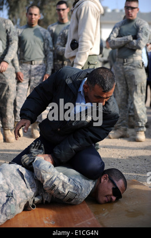 A member of an Iraqi emergency response unit (ERU) demonstrates fastening handcuffs on U.S. Army Cpl. Antony Powell during trai Stock Photo