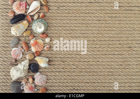 Sea shells and stones on background of rope closeup Stock Photo
