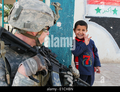 An Iraqi boy speaks with a U.S. Soldier at the Al Tatawori school in Hor Albosch, Iraq, Feb. 13, 2010. The Soldier, who is assi Stock Photo