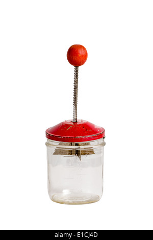 Antique nut chopper with a red handle with a glass jar on a solid