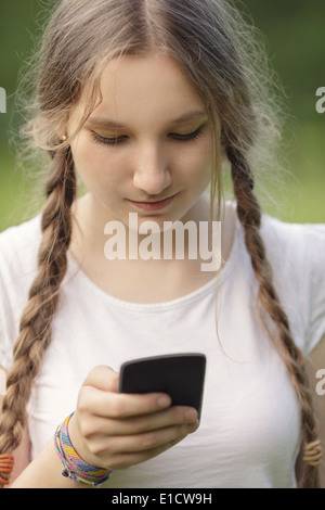 teen girl using mobile phone outdoors in park Stock Photo