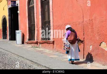 Indigenous lady wearing a hat walking along a street in San Miguel de Allende, Guanajuato, Mexico Stock Photo