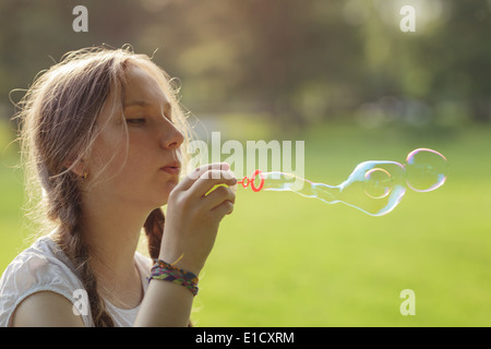 teenage girl blows soap bubbles in the park, summertime Stock Photo