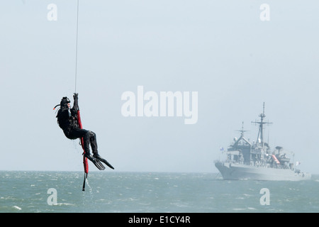 A U.S. Navy diver hangs from an SH-60B Seahawk helicopter assigned to the amphibious dock landing ship USS Harpers Ferry (LSD 4 Stock Photo