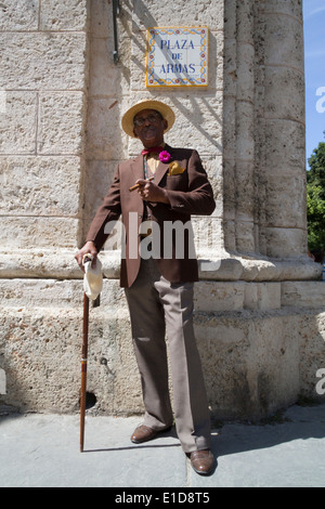 Cuban gentleman posing in vintage suit and straw hat whilst smoking a cigar in Plaza de Armas, in the Old Town, Havana Stock Photo