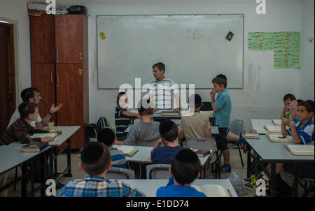 (140601) -- JERUSALEM, June 1, 2014 (Xinhua) -- Tzviel Noyman (C) talks with his teacher (1st L Rear) when leading a class of Jewish religion at Torat Moshe elementary school in Beit Shemesh, about 20 km from Jerusalem, on May 29, 2014. Tzviel Noyman is an Israeli Ultra-Orthodox boy in a family with six children, three boys and three girls. He is ten years old this year and a grade three pupil of Torat Moshe elementary school, which is only opened to Jewish children. Tzviel has eight classes each day, including Hebrew, English, mathematics and Jewish religion, which has four classes each day i Stock Photo
