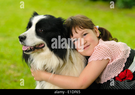 Vintage dressed little girl with border collie dog in the garden Stock Photo