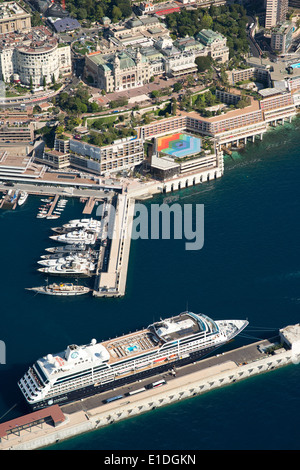 AERIAL VIEW. Cruise ship moored to a floating pontoon across from the Fairmont Hotel and the Monte-Carlo Casino. Principality of Monaco. Stock Photo