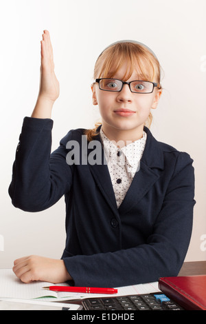 Little blond schoolgirl with glasses raises her hand Stock Photo