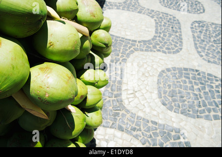 Bunch of fresh green Brazilian coco verde coconuts hanging in bright midday sun at Ipanema Beach boardwalk Rio de Janeiro Brazil Stock Photo