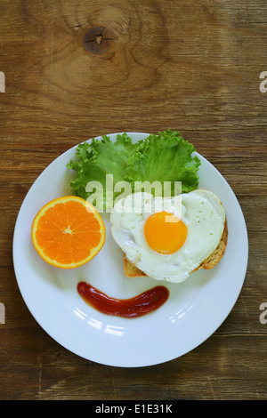 funny face serving breakfast, fried egg, toast and green salad Stock Photo