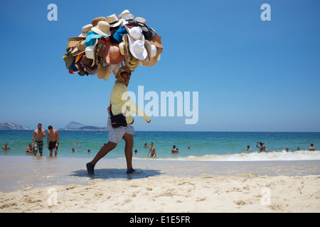 RIO DE JANEIRO, BRAZIL - JANUARY 22, 2014: Beach vendor selling hats walks carrying his merchandise on Ipanema Beach. Stock Photo