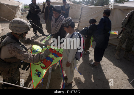 U.S. Marine Corps 1st Sgt. Jonathan Wyble assists an Afghan child with his kite on kite day in Marjah, Afghanistan, Oct. 10, 2 Stock Photo