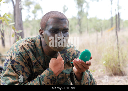 U.S. Marine Corps Lance Cpl. Michael Ellmer, assigned to Alpha Co., 1st Battalion, 3rd Marine Regiment, applies camouflage pain Stock Photo