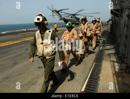 U.S. Marines prepare to board a CH-53E Super Stallion helicopter assigned to Helicopter Marine Medium Squadron (HMM) 165 aboard Stock Photo