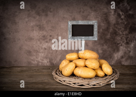 Potatoes on a table with blank price-board - isolated on white Stock Photo