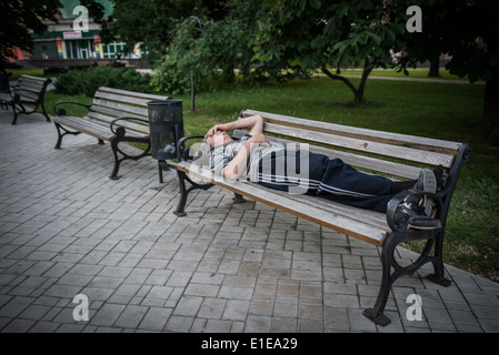 Dunk man sleeping on a bench in Gorky Park, Donetsk, Ukraine Stock Photo