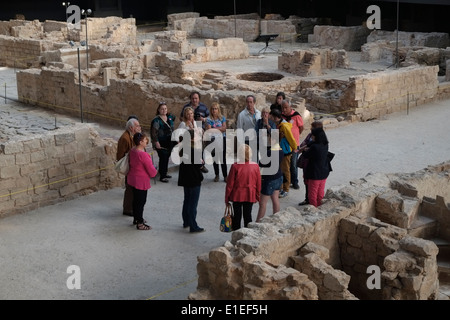 A group of tourists stand amid archaeological ruins which were part of the la Ribera district that was demolished in the early 18th century after the defeat of Catalonia in the War of Succession in 1714 inside the covered Mercat del Born a former public market constructed with iron in the Catalan modernism style located in the eastern side of la Ribera neighborhood in Barcelona Catalonia Spain Stock Photo